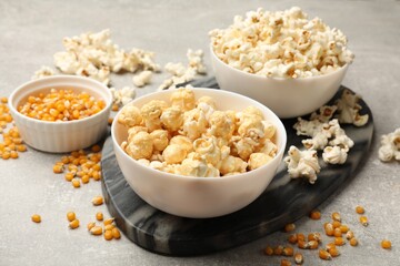 Wall Mural - Tasty popcorn and corn kernels on light grey table, closeup