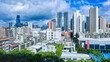 A modern city skyline featuring numerous high-rise buildings under a partly cloudy sky, showcasing urban architecture.