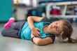 © Prazis Images - Young Girl with Child Chest Pain Lying on Gym Floor