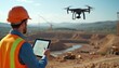 © Vadym - Engineer in safety vest, hard hat controls drone with tablet. UAV flies over construction project site, monitors excavation. Heavy equipment works on earthmoving. Man oversees building progress,