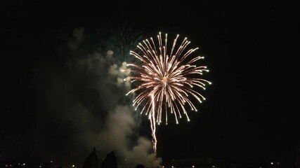 One beautiful golden firework shell bursts in a spectacular pyrotechnic display lighting up the night sky for a festive holiday event and celebration