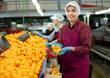 © JackF - Smiling young female sorter working on citrus sorting line in agricultural produce processing factory, holding pile of ripe mandarins
