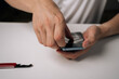 © dikushin - Skilled technician carefully removing damaged tempered glass screen protector from smartphone using precision repair tool, demonstrating professional device maintenance, close-up.