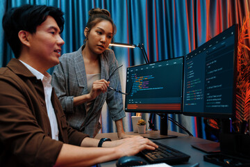 IT developers discussing with point to intelligent website development coder system running data online two screens information technology at neon light room at modern office. Infobahn.