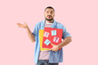 © Pixel-Shot - Portrait of thoughtful young man holding folders with question marks on pink background