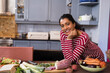 © wavebreak3 - Smiling woman in striped shirt preparing fresh vegetables in modern kitchen