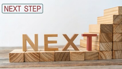wooden blocks spelling the word 'next' with steps in the background for motivation and growth in per