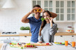 © BestForYou - Couple in the kitchen preparing a dish from healthy vegetables, chatting happily, balanced nutrition.