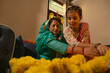 © IndiaPix - Mother and daughter arranging marigold flowers together during festive decoration, sharing cultural traditions and bonding at home