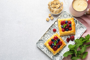Wall Mural - Tasty puff pastries with berries, mint, brown sugar and coffee on light grey table, flat lay. Space for text
