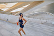 Determined hispanic sportswoman running up stairs with a shaker bottle in her hand in city