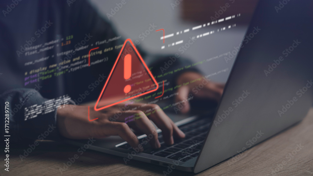 Close-up of hands typing on laptop with warning error icon and code ...