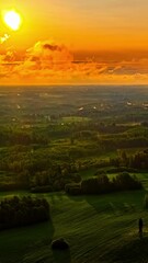 Wall Mural - An orange sunrise over a green landscape, morning dew rising here and there like small puffs of steam.