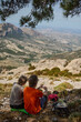 © Taras Grebinets - Hikers Resting on Mountain Overlook with Scenic Valley View