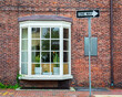 Charming red brick wall with large bay window and street sign in Cambridge, Massachusetts, USA
