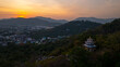 Aerial view of Sunset above Khao Rang viewpoint. view of a town nestled among lush green mountains at sunset, with a Pavilion structure perched on the hillside at Phuket town at Dusk