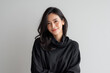 © Gita - Portrait of a smiling woman in black against a gray backdrop