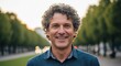 © iCreative - Smiling middleaged man with curly hair in outdoor park setting