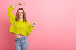 © deagreez - Cheerful young woman in a trendy yellow sweater posing against a vibrant pink background with a joyful smile