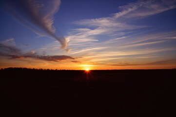 Wall Mural - Vibrant Evening Sky Above Open Pasture With Shadowed Terrain