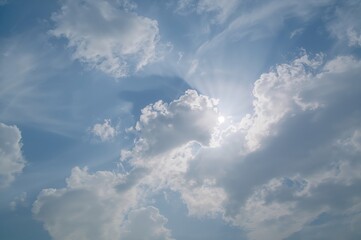 Wall Mural - bright sun shining through picturesque clouds in a clear blue sky