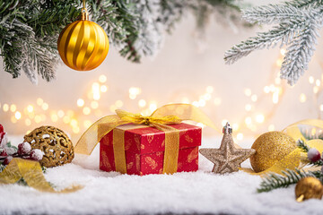 Wall Mural - festive red present with golden ribbon surrounded by gold ornaments, glittering star, and snowy pine