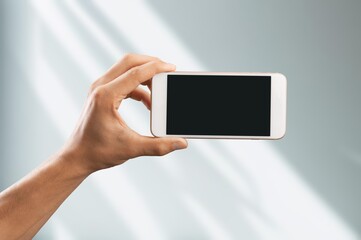 Hand showing modern smartphone with blank screen