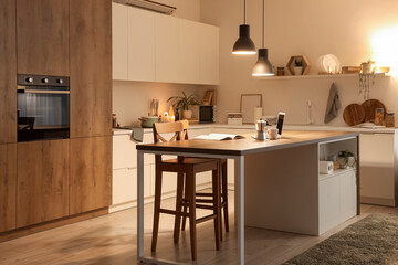 Wall Mural - Interior of kitchen with table, counters and glowing lamps in evening