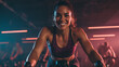 © Facundo - A determined-looking woman on a cycling bike in a spin class, catching the camera with a quick, powerful smile.
