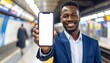 © ary - Smiling man in suit holding phone on subway platform.