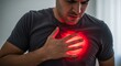 © Hamid - A man clutches his chest in pain, with a glowing red area indicating discomfort or a heart condition.