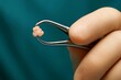 © Kanishka - A hand carefully grips tweezers holding a small tissue-like specimen, emphasizing surgical precision, delicate handling, and clinical accuracy.