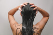 © Reezky - Back portrait of a young Asian woman with long hair, getting her hair washed using shampoo.