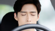© Nakarin - Young driver advice concept with calm man closing eyes sitting inside car steering wheel