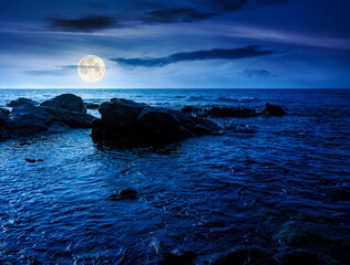 Wall Mural - sea coast with rocks and boulders at night. calm summer vacation background at the seashore. wonderful scene for relax and leisure at the seaside in full moon light