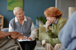© Seventyfour - Middle aged Caucasian woman with short blond hair observing young man with red hair sitting and holding hand to mouth during counseling session