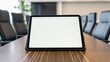 © thanawat - A tablet on a conference table in a modern meeting room, highlighting a professional and collaborative environment.