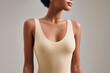 © Nyxoria - Woman in neutral-toned sleeveless top against a gray backdrop. The focus is on the garment's fit and fabric, highlighting elegance and comfort.