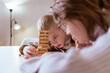 © looking2thesky - A mother and her son with hearing aids share a joyful moment playing board games together. A heartwarming scene of inclusive family bonding, love, and adaptive play