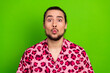 © deagreez - Young man with playful expression wearing vibrant pink shirt on a colorful green background exuding confidence and style