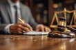 © Minerva Studio - Lawyer signing documents with gavel and scale in background