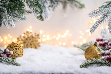 Wall Mural - glittering gold ornaments and snowflakes rest on snowy ground with frosted pine branches and soft gl