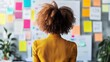 © Sobah - Person looking at a wall covered in colorful sticky notes.