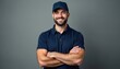 © Viktor - Bearded male worker in navy blue polo shirt and cap, arms crossed. Confident service technician delivery driver smiles at camera. Portrait of pro employee in uniform against grey background.