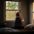 © bangku - Elderly man sits pensively by the window in quiet contemplation
