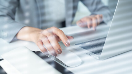 Wall Mural - Business woman hand holding and clicking wireless computer mouse, working on laptop, surfing the internet, searching online information at office, close up