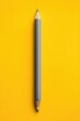 © Saadisah - A vertically oriented, dark gray pencil with sharpened points sits centrally on a vibrant yellow background.  Clean, minimalist aesthetic