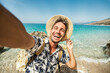 © Davide Angelini - Handsome young man taking selfie picture with smart mobile phone outside - Happy tourist enjoying summer holiday at the beach - Traveling and technology life style concept