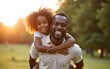 © Thomas - Portrait of happy black father carrying daughter on back outdoors. Family happiness love concept. High quality