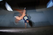 © Seventyfour - Girl performing dynamic one handed handstand breakdance move under urban overpass, long curly hair swinging, energetic movement captured mid air, Gen Z youth culture
